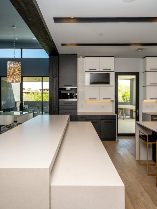 Home 9 modern kitchen with oversized concrete waterfall island, matte black and white cabinetry, integrated appliances, and warm wood flooring
