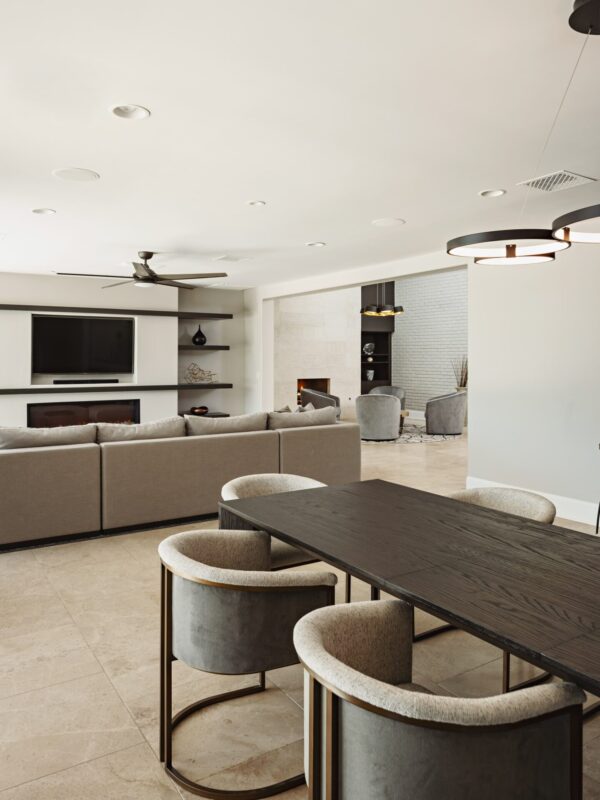 Home 8 open-concept dining and living area with dark wood dining table, upholstered chairs, and fireplace seating area beyond